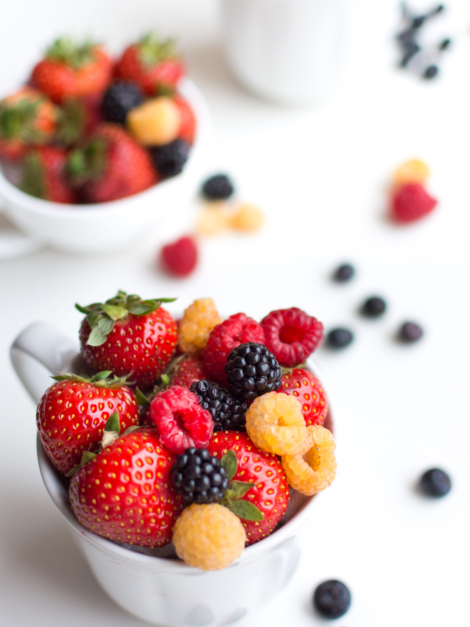 Vibrant shot of colorful healthy fresh berries in a cup on a white background